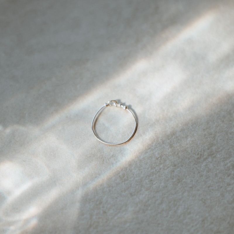 Bague anneau fin lisse Tiggy en argent massif isolée sous un rayon de soleil poétique.