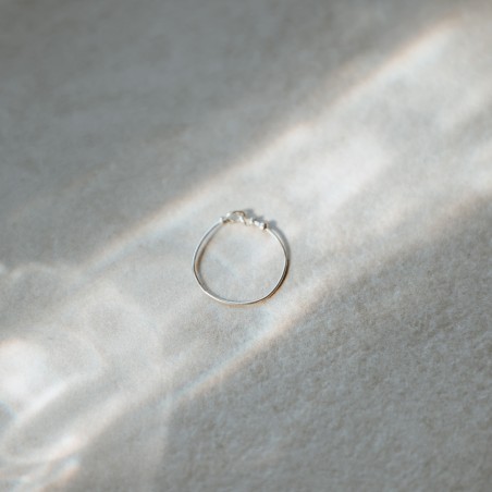 Bague anneau fin lisse Tiggy en argent massif isolée sous un rayon de soleil poétique.