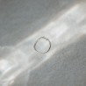 Bague anneau fin lisse Tiggy en argent massif isolée sous un rayon de soleil poétique.