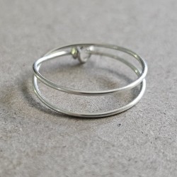 Bague double tour Cece en argent 925 massif posée à plat, dévoilant son fermoir double boucle artisanal.