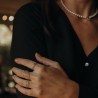 Zoom sur un jeu de bagues épurées en argent 925 porté avec une robe noire et un collier de perles.