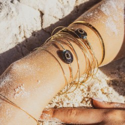 Jonc Una en gold filled 14K avec labradorite et grenat sertis porté en accumulation sur la plage