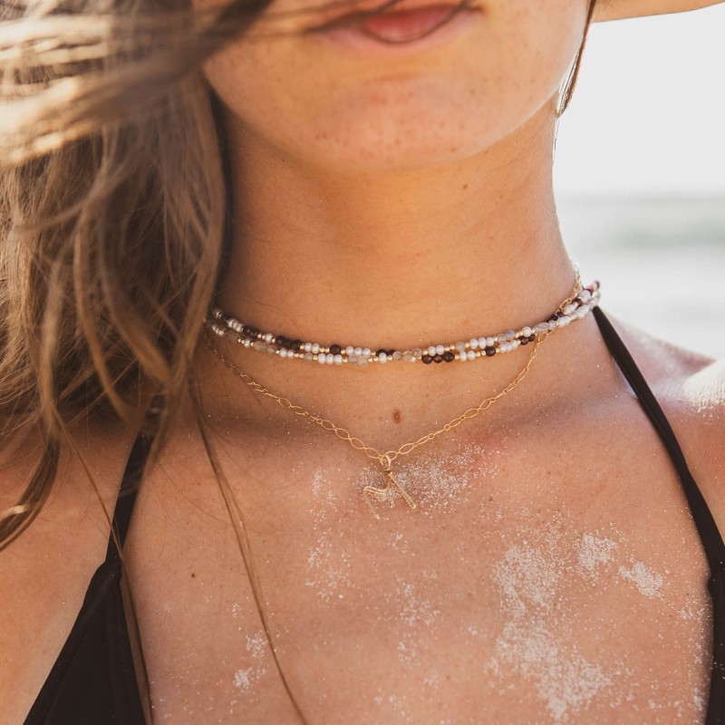 Ras de cou entremêlés perles de culture et pierres de labradorite et grenat, associé à un collier à chaîne fine et lettre M.