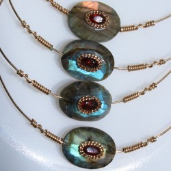 Détails des labradorites serties de grenats entourés d'une chaine maille plate dorée et tortillons signature