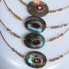 Détails des labradorites serties de grenats entourés d'une chaine maille plate dorée et tortillons signature