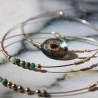 Zoom sur le sertissage du grenat bordeaux au centre de la pierre de labradorite et l'enroulement de fil d'or artisanal.
