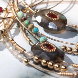 Gros plan incliné des trois bracelets joncs mettant en valeur les reflets bleutés de la labradorite et l'éclat des turquoises.