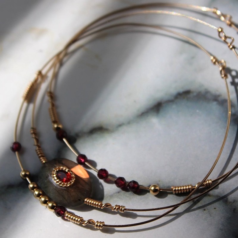 Set Maeve en lumière rasante mettant en valeur les reflets irisés de la labradorite centrale sertie et perles de grenat.