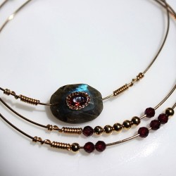 Zoom sur les détails artisanaux du set Maeve, enroulement de fil d'or 14K autour de grenat facettées et des billes dorées.