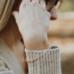 Détail accumulation de joncs fins en or recyclé pour un effet semainier solaire.