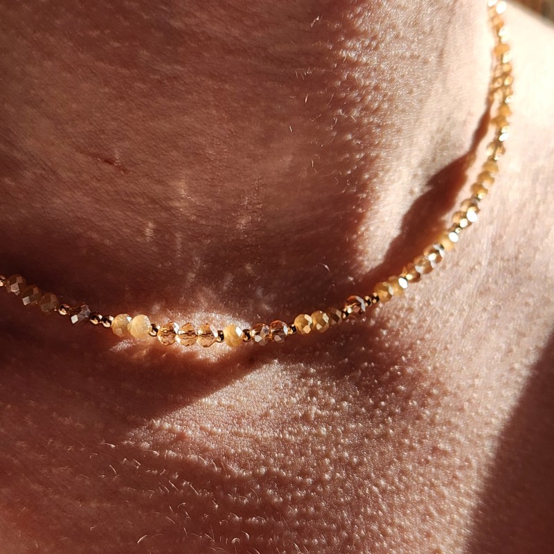 Gros plan Collier Blossom Halo Champagne en Gold Filled 14k et perles de verre beiges porté au cou