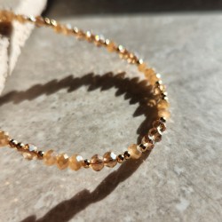 Collier Blossom Halo Champagne avec perles de verre mates et transparentes sur un fond type marbré